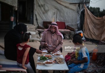 الفلسطيني عاطف الكورا وعائلته يفطروا بجوار حطام منزلهم المدمر .