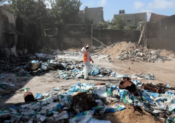 عمال فلسطينيون يزيلون المخلفات الكيمائية والمبيدات الزراعية الناجمة عن القصف "الإسرائيلي" للمصانع خلال العدوان الأخير