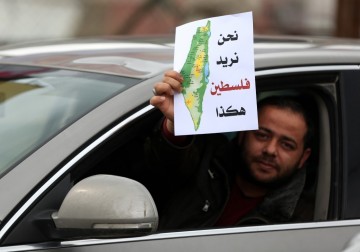 نشطاء يوزعون صورًا لخارطة فلسطين التاريخية وسط نابلس