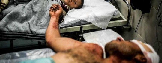 أب فلسطيني يمسك يد طفله الناجي من آلة القتل 