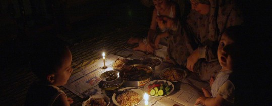 عائلة تتناول الطعام على إنارة الشموع بسبب انقطاع التيار الكهربائي