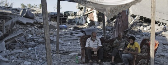 مواطنون يجلسون على أطلال منزلهم المدمّر جراء عدوان 2014