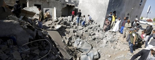 يمنيون يقفون فوق أنقاض بيوت مرتها عاصفة الحزم  قرب مطار صنعاء