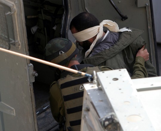 جندي صهيوني يعتقل مواطنًا فلسطينيًا - ارشيف