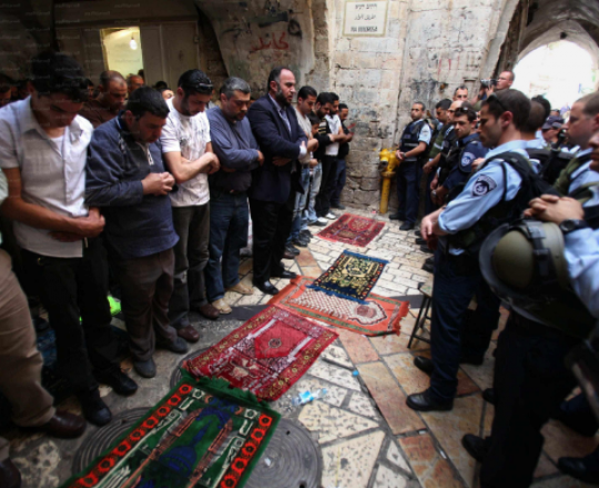 مقدسيون يُؤدّون الصلاة أمام حاجز لقوات الاحتلال على أحد أبواب الأقصى - يوليو 2014