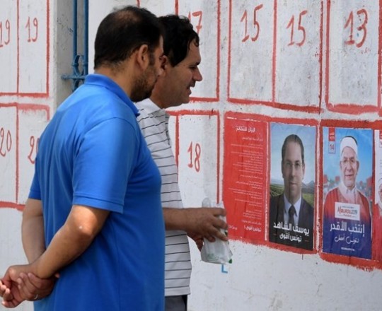 مواطنون تونسيون ينظرون إلى صور مرشحين للانتخابات الرئاسية - أ.ف.ب