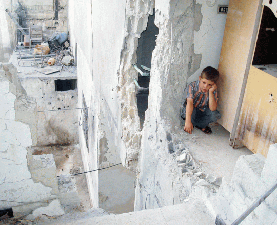 طفل سوري يجلس في بيته المدمّر جراء القصف